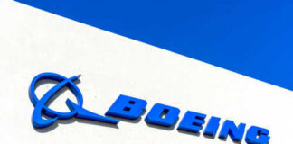 Boeing logo on a white building, blue sky.