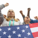 People raising fists with American flag nearby.
