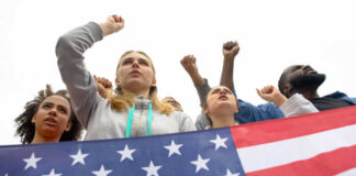 People raising fists with American flag nearby.