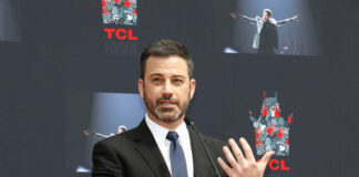 A man in a suit speaking at a podium during an event at TCL Chinese Theatre