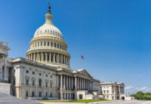 Tariff Showdown: GOP Split Shakes House U.S. Capitol building with American flag, blue sky.
