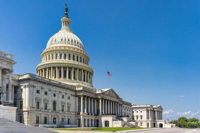 U.S. Capitol building with American flag, blue sky.