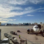 Airport runway with airplane and Las Vegas skyline.