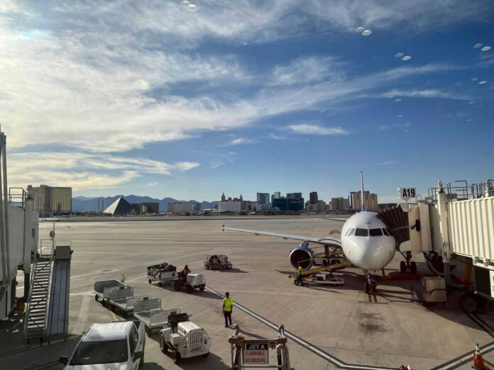 Airport runway with airplane and Las Vegas skyline.