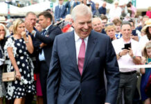 Smiling man in suit surrounded by people outdoors