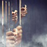 Hands gripping prison bars in smoky atmosphere