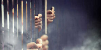 Hands gripping prison bars in smoky atmosphere