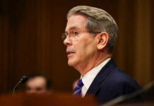 Russian Oil Waiver: Strategic Shift Amidst Sanctions Man in suit speaking at a microphone indoors