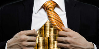 Businessman revealing gold coins under his shirt