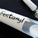 A glass container labeled 'Fentanyl' with a white powder inside