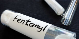 A glass container labeled 'Fentanyl' with a white powder inside