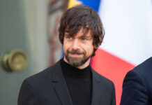 A man in a black suit smiling outdoors