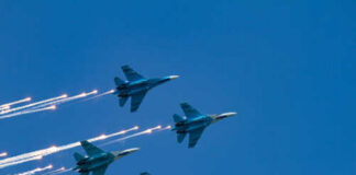 Four military jets flying in formation with smoke trails against a blue sky