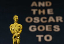 Close-up of an Oscar statue with the phrase 'And the Oscar goes to' in the background