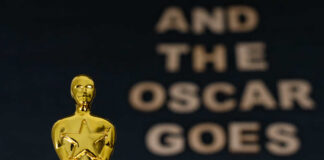 Close-up of an Oscar statue with the phrase 'And the Oscar goes to' in the background