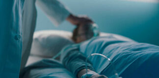 A medical professional attending to a patient in a hospital bed