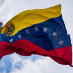 Venezuelan flag waving against a cloudy sky
