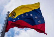 Venezuelan flag waving against a cloudy sky