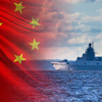 A Chinese naval ship sailing on the ocean with the Chinese flag in the background