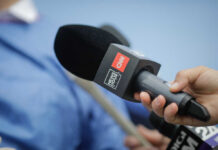 A hand holding a microphone with a CNN logo, ready for an interview