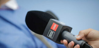 A hand holding a microphone with a CNN logo, ready for an interview
