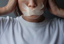 A person with tape over their mouth, symbolizing silence or oppression