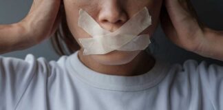 A person with tape over their mouth, symbolizing silence or oppression
