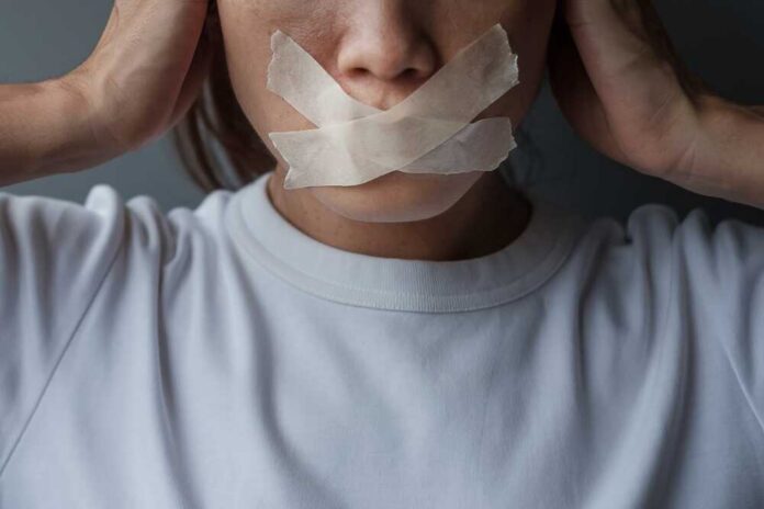 A person with tape over their mouth, symbolizing silence or oppression