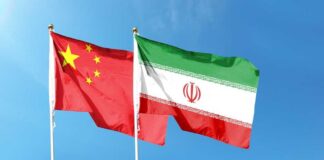 Flags of China and Iran waving against a blue sky