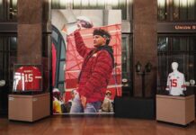 NFL SHOCKER: Mahomes’ Unbelievable Recovery Timeline Display of Kansas City Chiefs memorabilia with a large poster of a player holding a trophy