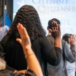 Participants raising their hands during a citizenship oath ceremony