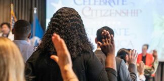Participants raising their hands during a citizenship oath ceremony