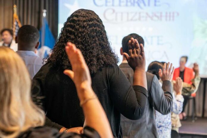 Participants raising their hands during a citizenship oath ceremony