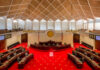 Interior view of a legislative chamber with red carpet and wooden accents