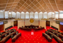 Interior view of a legislative chamber with red carpet and wooden accents