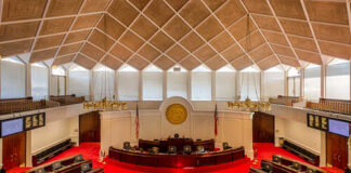 Interior view of a legislative chamber with red carpet and wooden accents