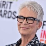A smiling woman with short gray hair and glasses at a film awards event