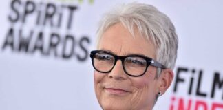 A smiling woman with short gray hair and glasses at a film awards event
