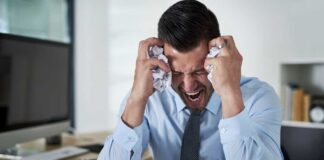 Frustrated businessman holding his head in an office filled with paperwork