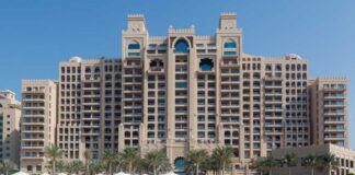 A luxury hotel by the beach with sun loungers and palm trees