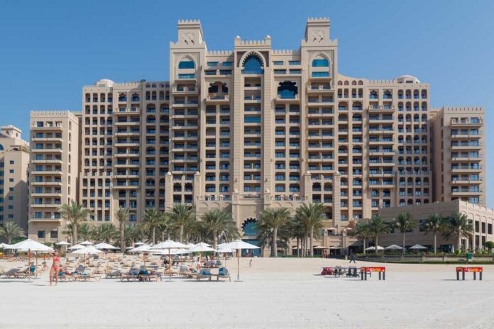 A luxury hotel by the beach with sun loungers and palm trees