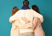 Three people embracing each other from behind against a teal background