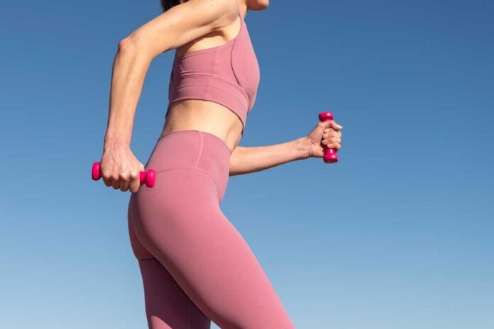 Woman exercising outdoors with pink dumbbells