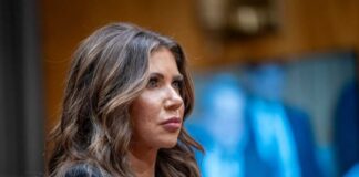 A woman testifying in a government hearing with a serious expression