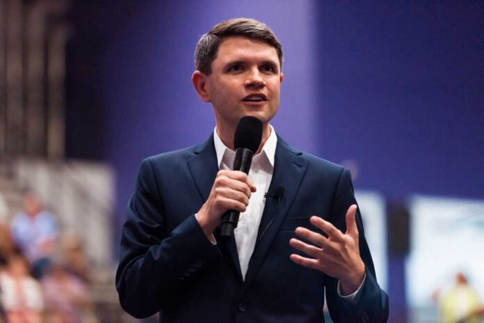 A man in a suit speaking into a microphone at a conference