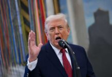 A man speaking passionately into a microphone with his hand raised