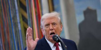 A man speaking passionately into a microphone with his hand raised