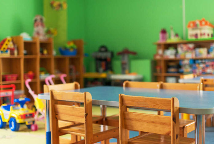 Brightly colored classroom with wooden tables and shelves filled with toys