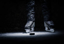 A pair of ice skates hovering above a hockey puck on the ice