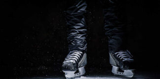A pair of ice skates hovering above a hockey puck on the ice